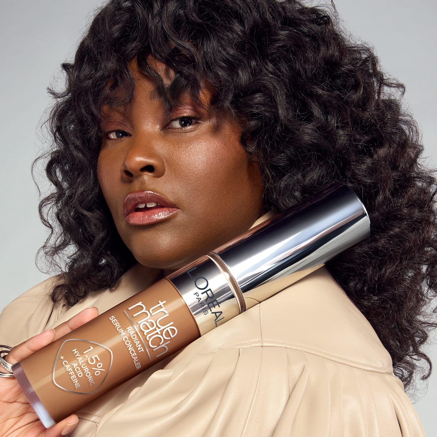 Eine junge Frau mit lockigen Haaren, die den Concealer 11N Deep in ihrer Hand hält